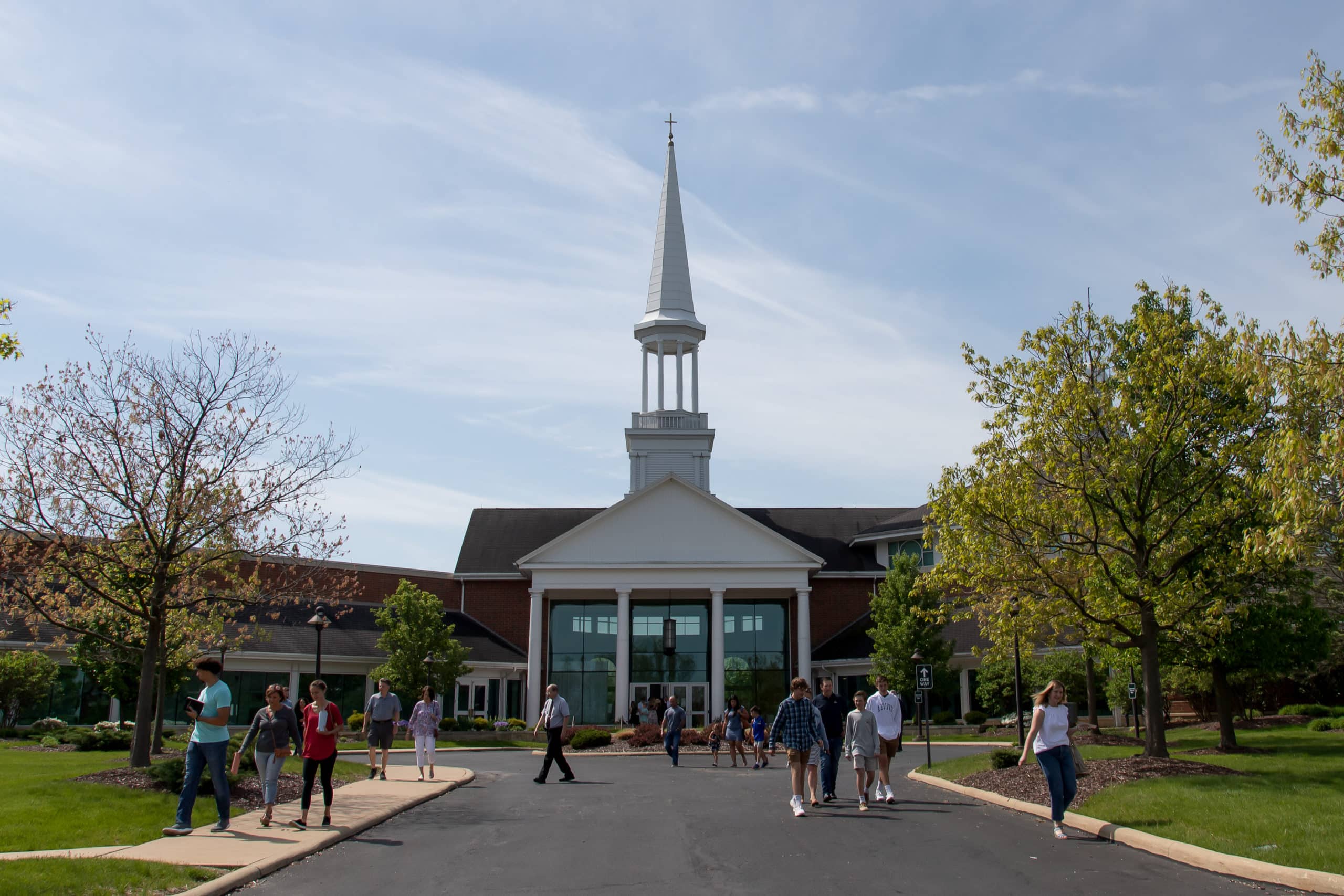 Attenders leaving a church service at Christ Community Chapel on a sunny day.